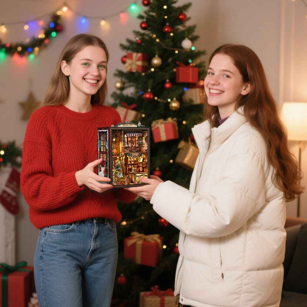 Two women exchanging a Christmas Shop book nook beside a decorated Christmas tree.