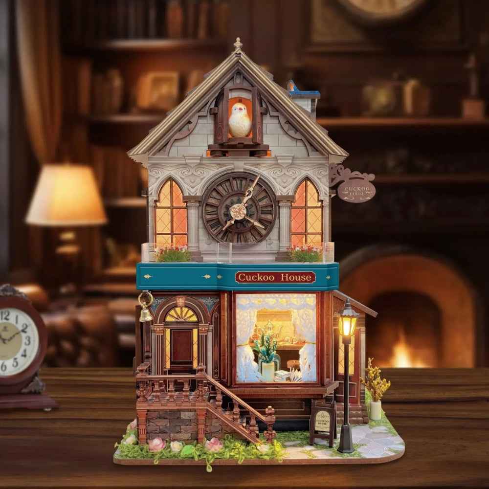 Cuckoo Clock House miniature building with a clock face, blue trim and warm shop-window lighting.