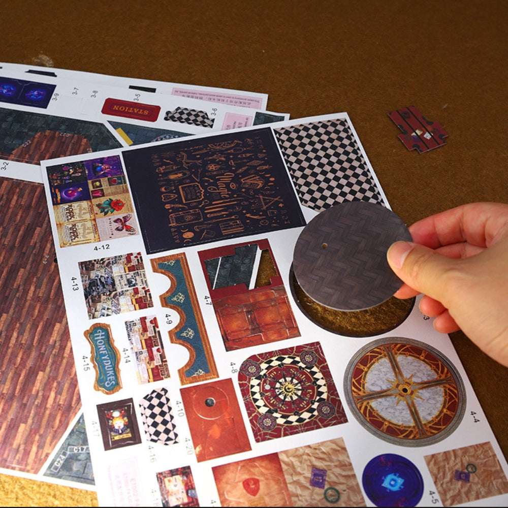 Hand holding a round component beside Magic Energy Station printed assembly sheets.