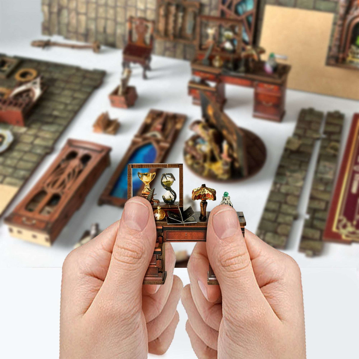 Hands holding a small Magic Studio furnishing beside wooden components.