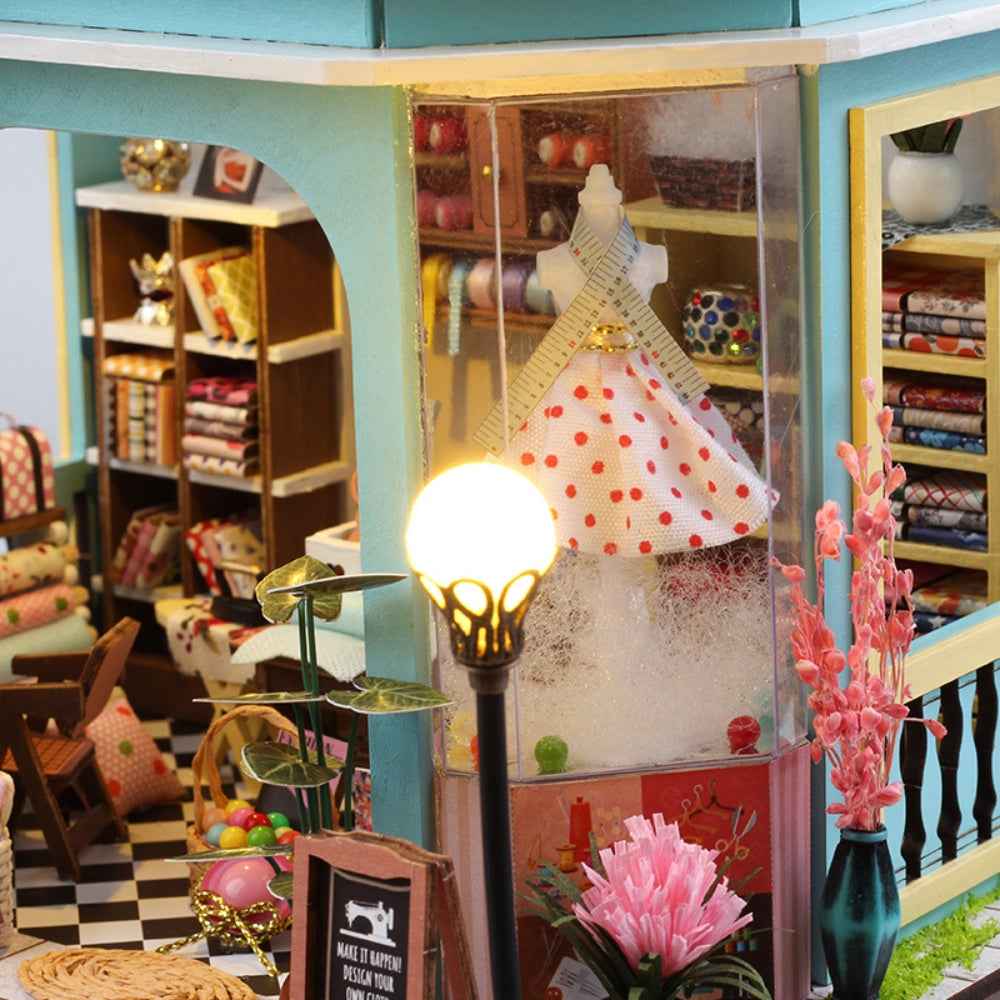 Tailor Shop window display with a polka-dot dress form and miniature fabric shelves.