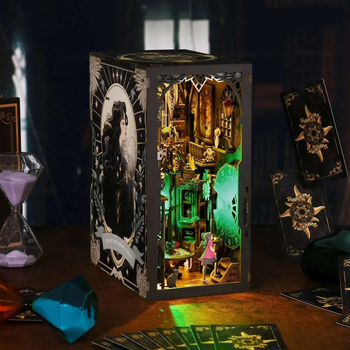 Angled Tarot Divination Society book nook beside decorative crystals and cards.