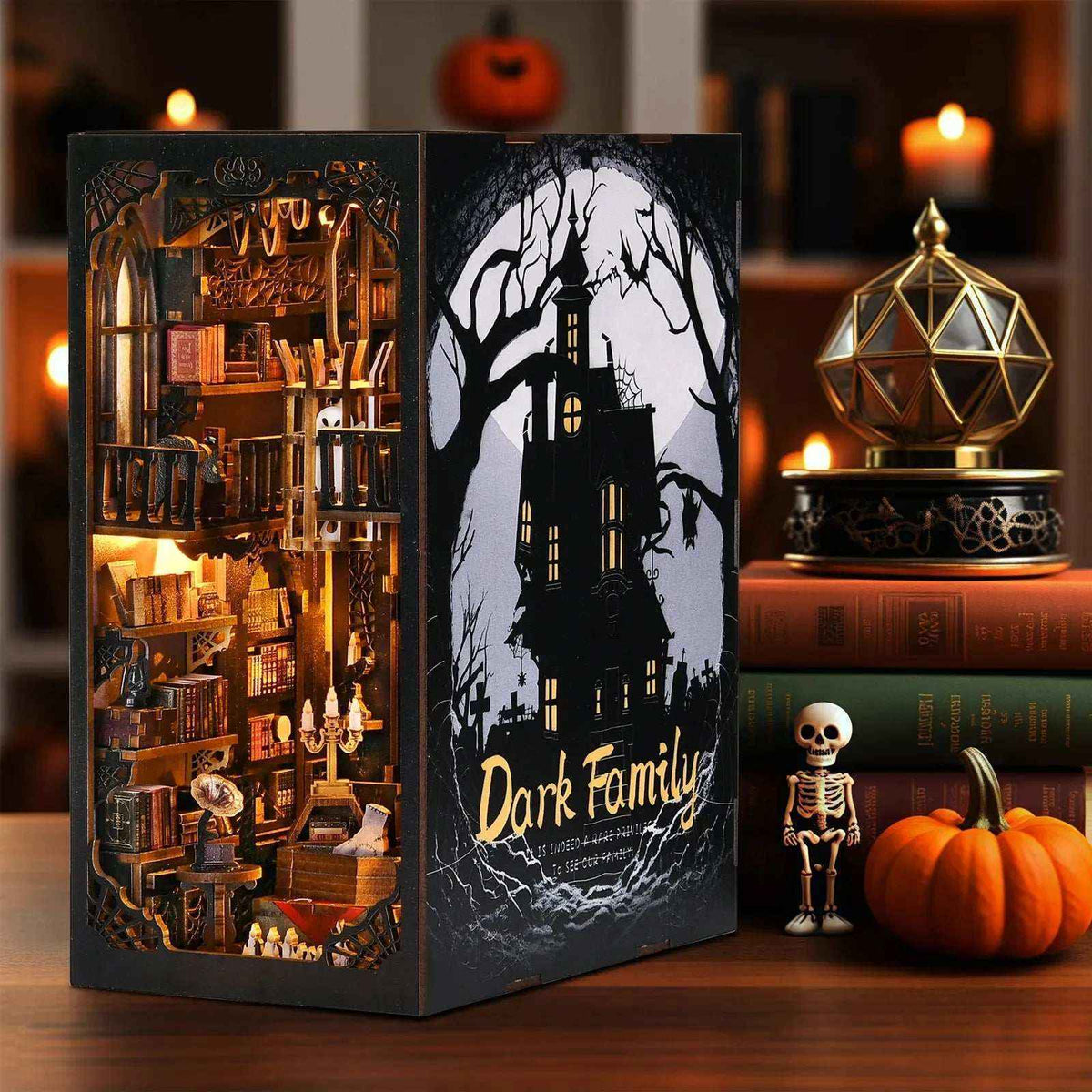 The Dark Family book nook beside a pumpkin, candles and a miniature skeleton.