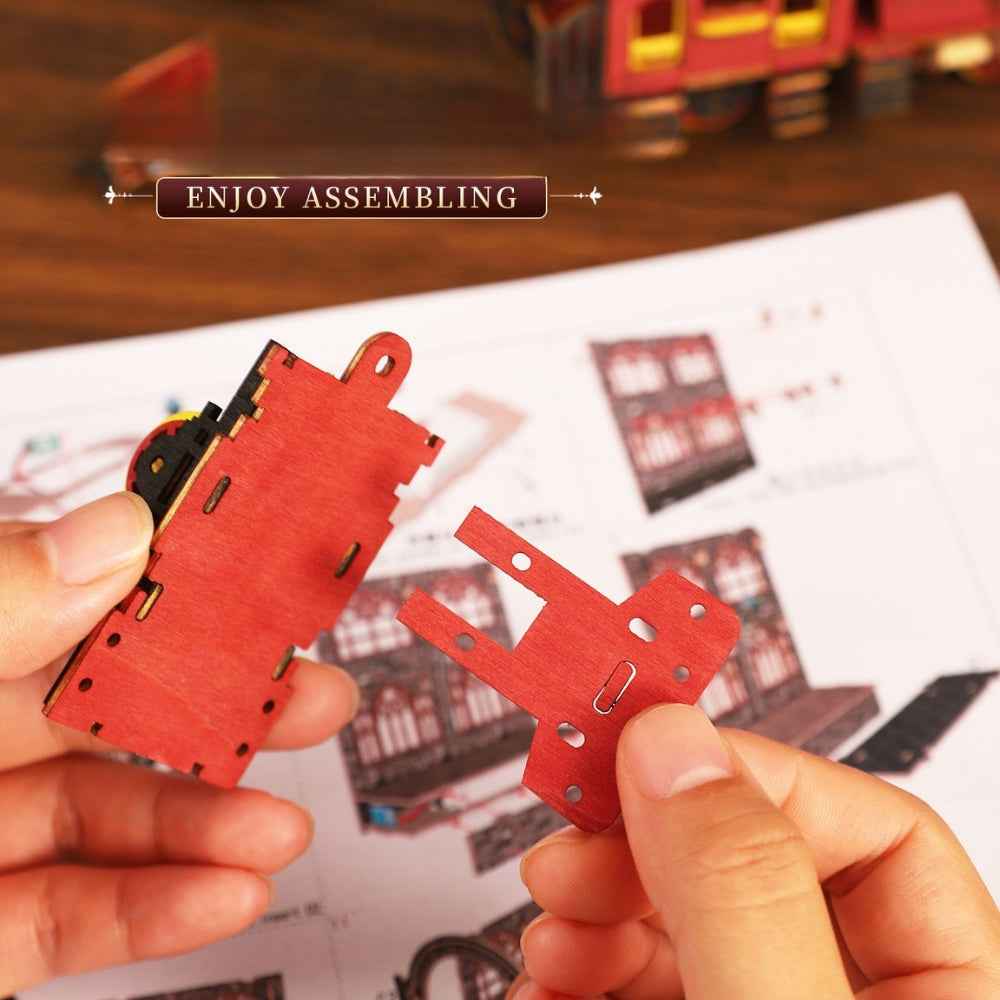 Hands joining red wooden components for the Zero Platform locomotive.