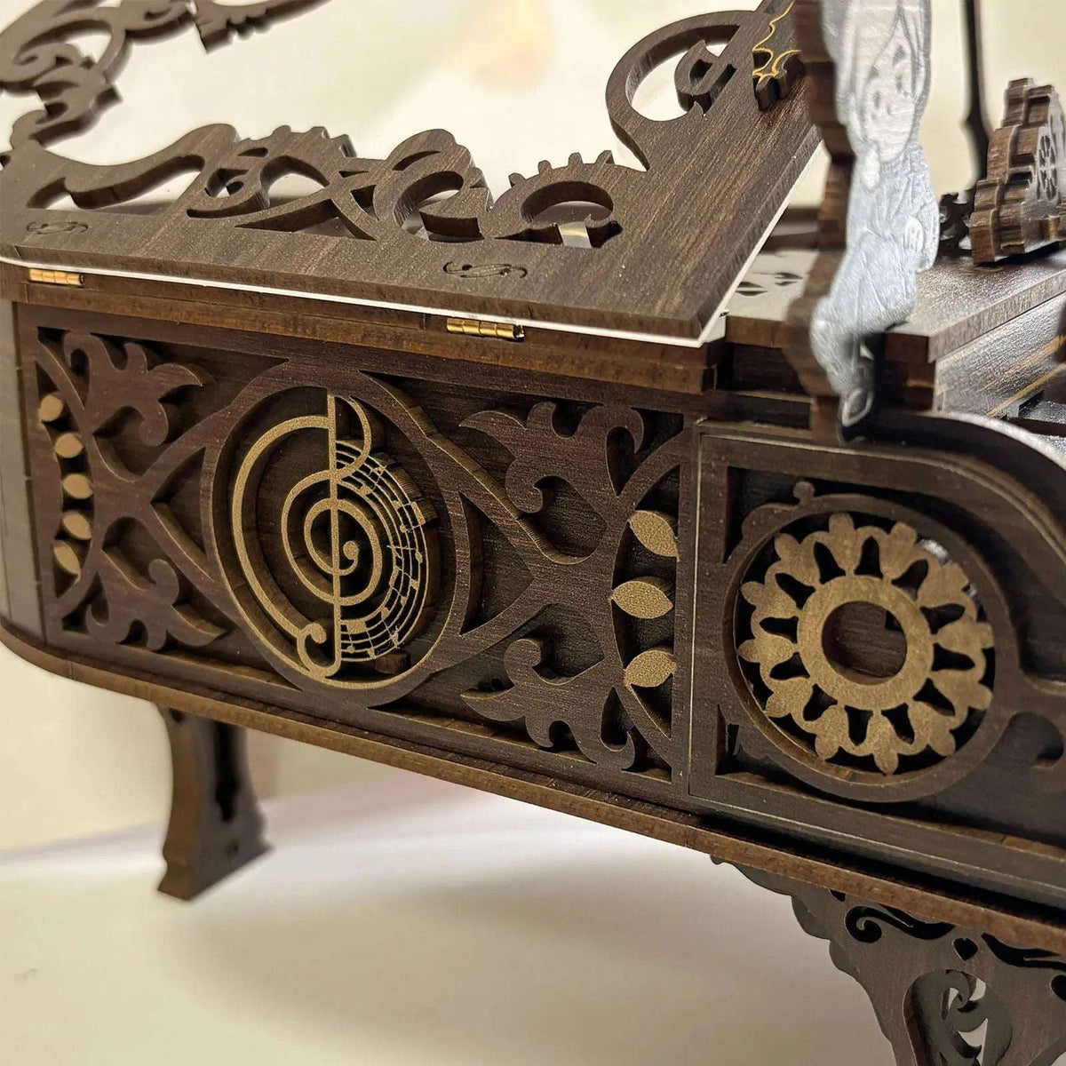 3D Piano side panel with scrollwork, a musical emblem and exposed wooden gear.