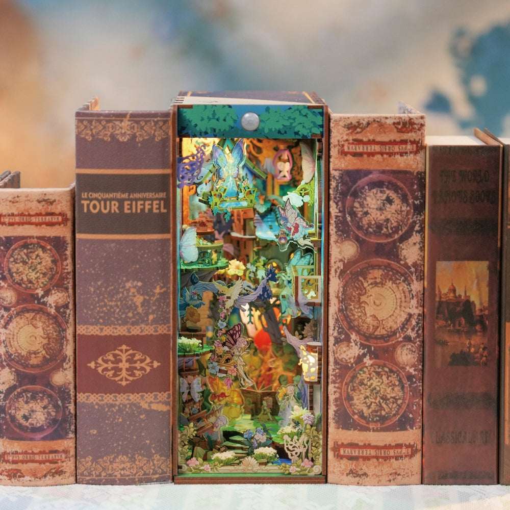 A Midsummer Night's Dream book nook between books, filled with miniature flowers and woodland buildings.