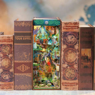 A Midsummer Night's Dream book nook between books, filled with miniature flowers and woodland buildings.