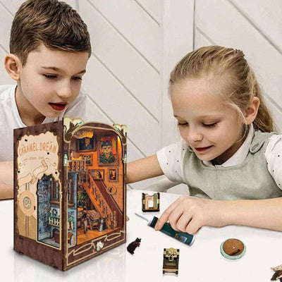 Two children assembling small parts beside a completed Caramel Dreams book nook.