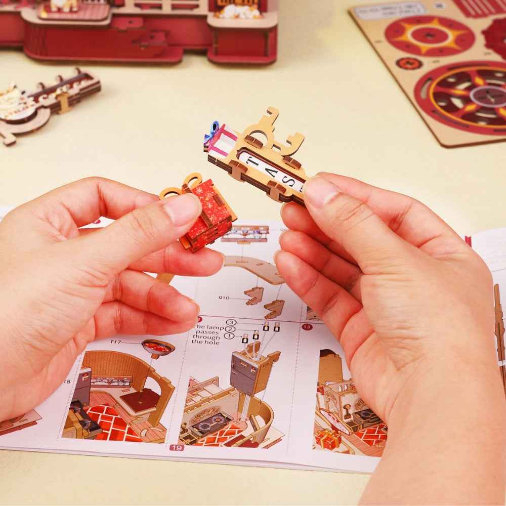 Hands assembling small Dessert Atelier components over illustrated instructions.