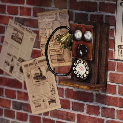 Miniature wall telephone and newspaper notices on the Fancy Train Platform brick wall.