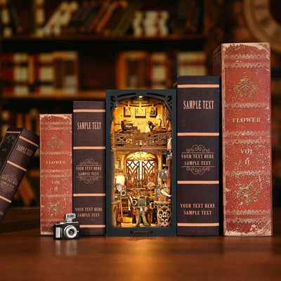 Film Darkroom book nook between books with a miniature camera beside it.