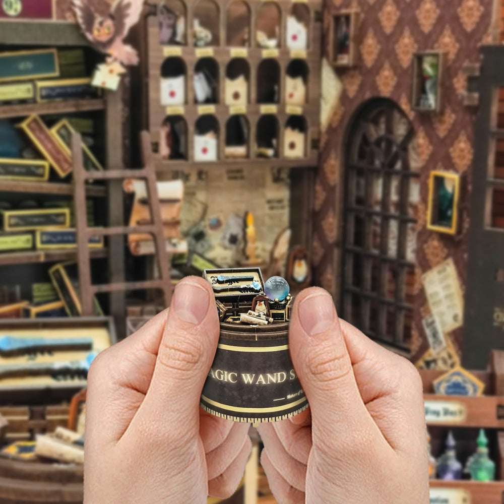 Hands holding a miniature cash register beside the Magic Wand Store interior.