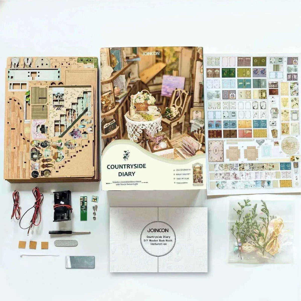 Pastoral book nook kit contents with wooden panels, printed decorations, lighting parts and instructions.