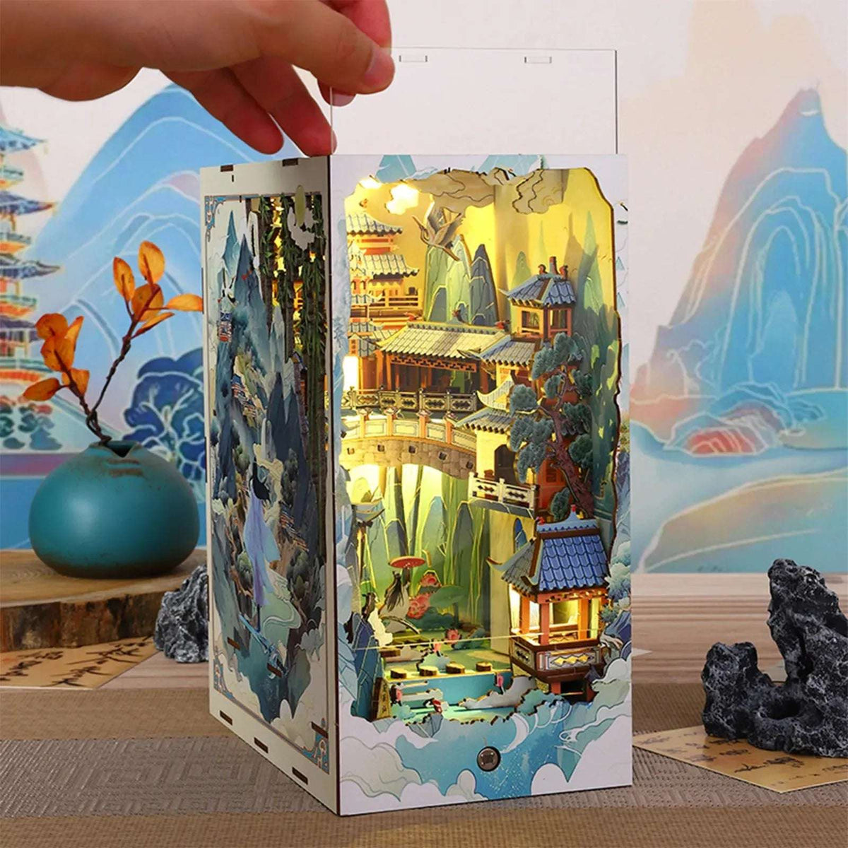 Hand lifting the clear cover from the Penglai Wonderland miniature landscape book nook.