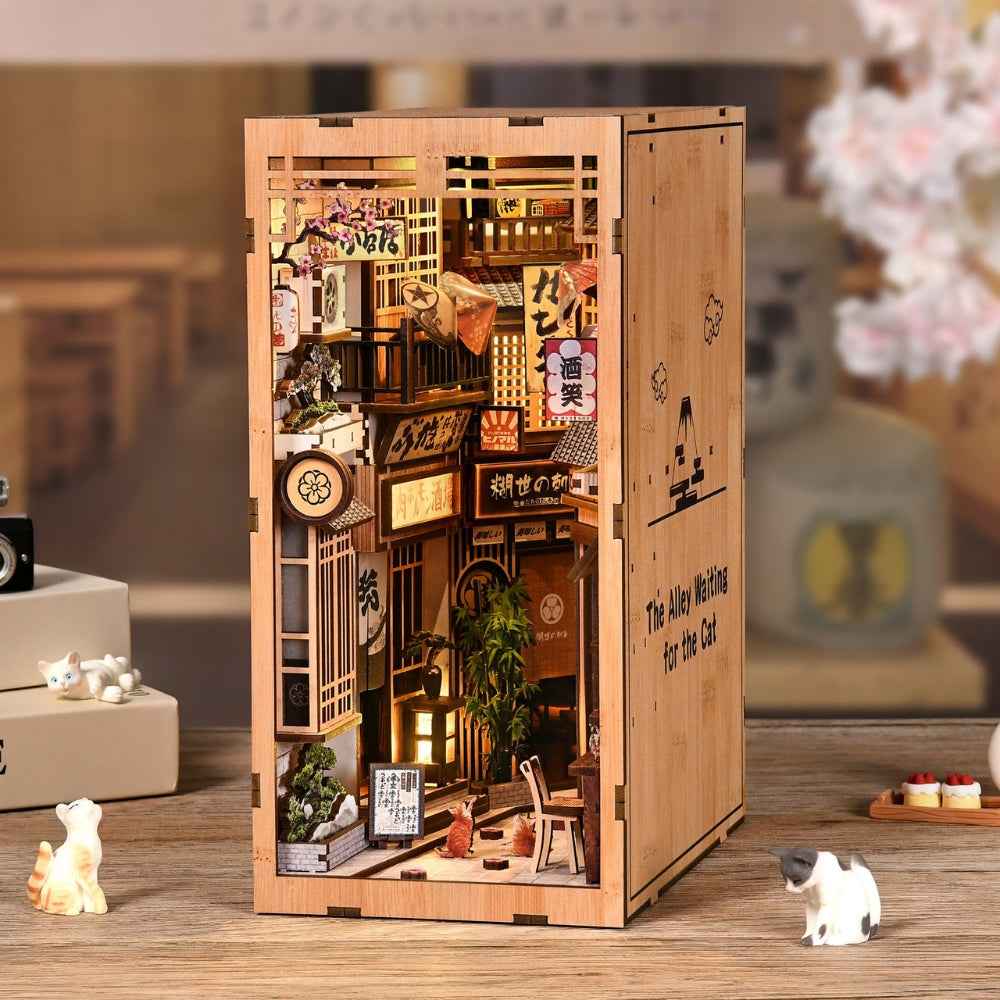 The Alley Waiting for the Cat displayed on a table with miniature cat figures nearby.