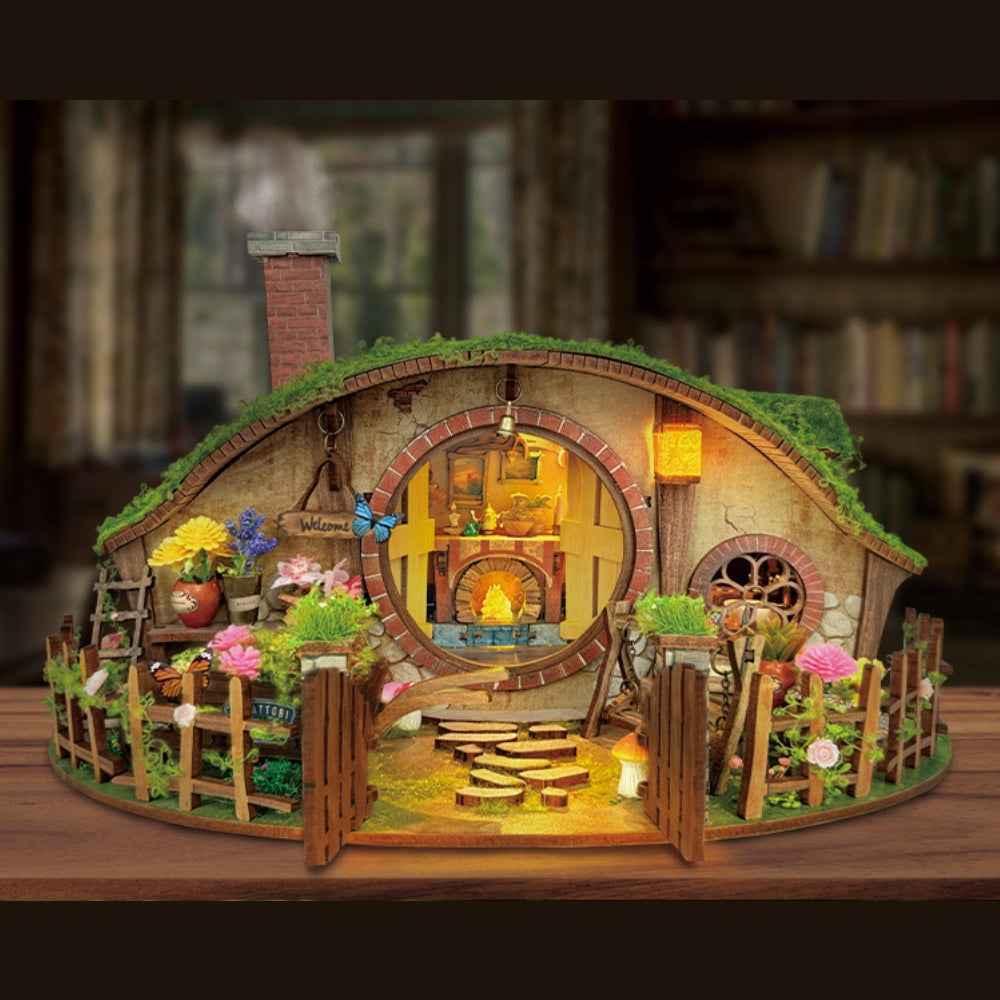 The Magic Ring House miniature cottage with a round doorway, grass-like roof and flower-filled garden.