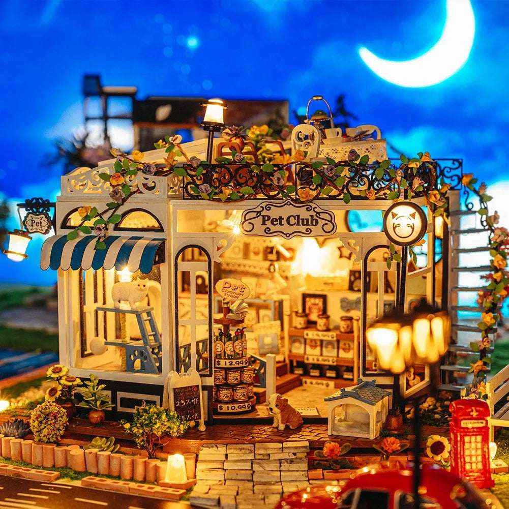 The Pet Club miniature shop with blue-and-white awnings and warm lights against a moonlit backdrop.