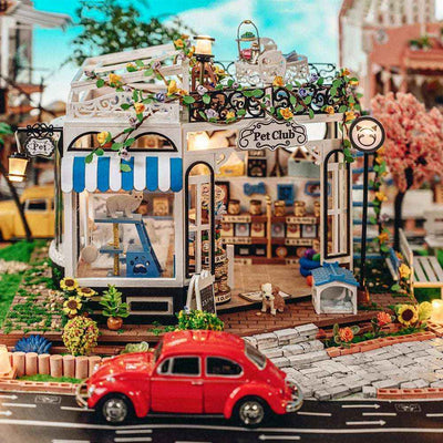 The Pet Club miniature storefront with plants, striped awnings and a red toy car on the street.