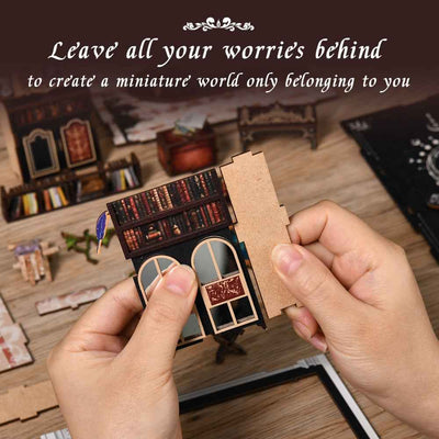 Hands assembling a wall panel with miniature shelves for The Realm of the Magic Book.