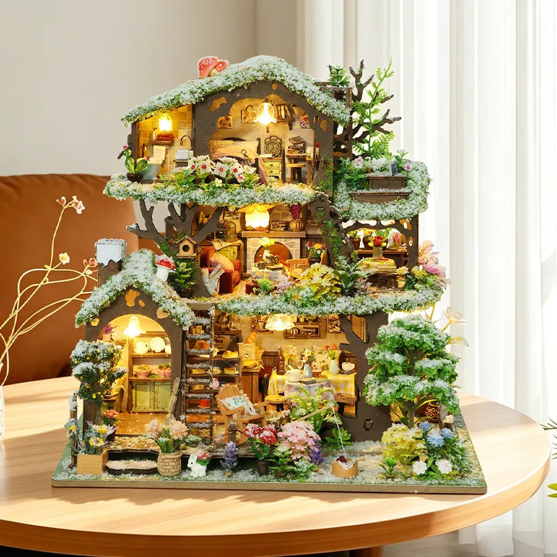 Time Treehouse snow-roof edition displayed beside a window, with white-tipped foliage and warm lights.