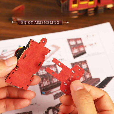 Hands joining red wooden components for the Zero Platform locomotive.